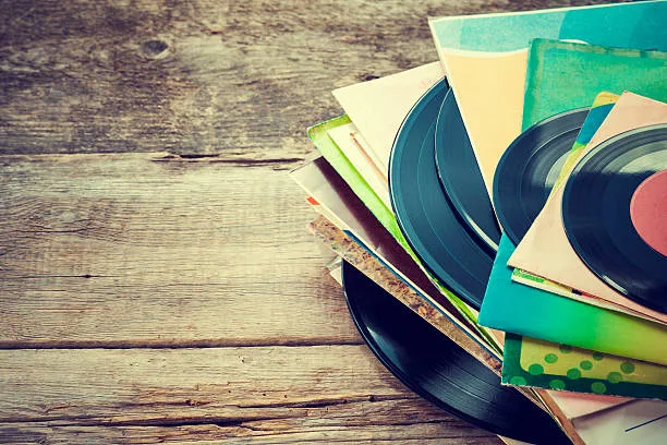 Vinyl records and sleeves spread over a wooden surface
